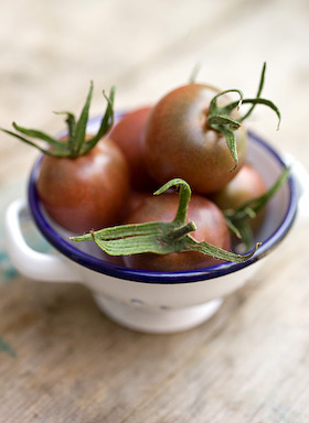 black cherry tomatoes in a miniature colander